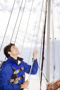 Man Hoisting Sail on Sailboat